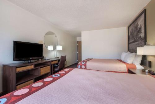 a hotel room with two beds and a flat screen tv at Super 8 by Wyndham College Station in College Station