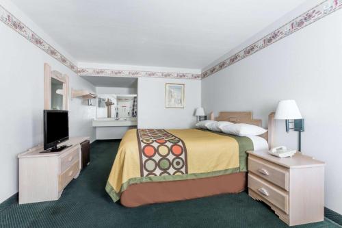 ein Hotelzimmer mit einem Bett und einem Flachbild-TV in der Unterkunft Super 8 by Wyndham Cottonwood in Cottonwood