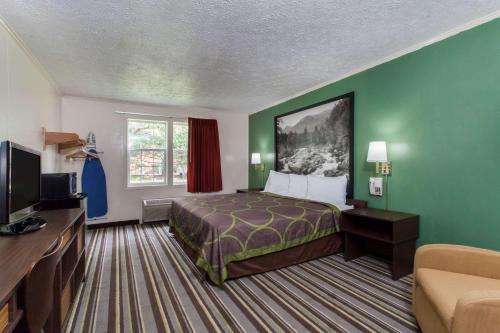 a hotel room with a bed and a television at Syracuse Inn in East Syracuse