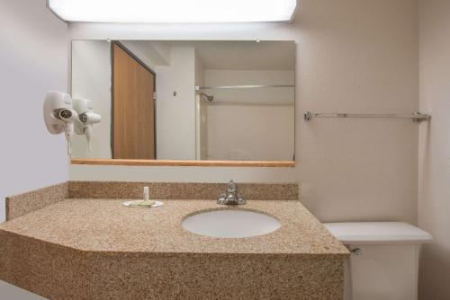a bathroom with a sink and a mirror at Super 8 by Wyndham College Station in College Station