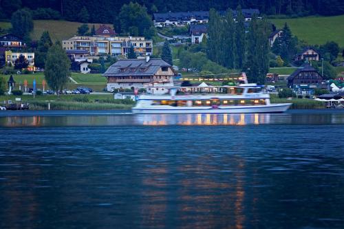 a white boat on the water in front of a town at Landhaus Danita in Bodensdorf