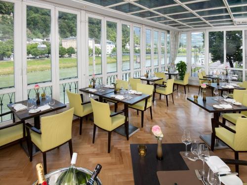 a restaurant with tables and yellow chairs and windows at Radisson Blu Hotel Altstadt in Salzburg