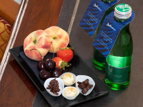 a plate of food with fruit and a bottle of wine at Radisson Blu Hotel Altstadt in Salzburg