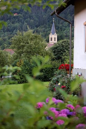 a church with a steeple in the background with flowers at Landhaus Danita in Bodensdorf
