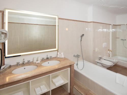 a bathroom with two sinks and a tub and a toilet at Radisson Blu Hotel Altstadt in Salzburg