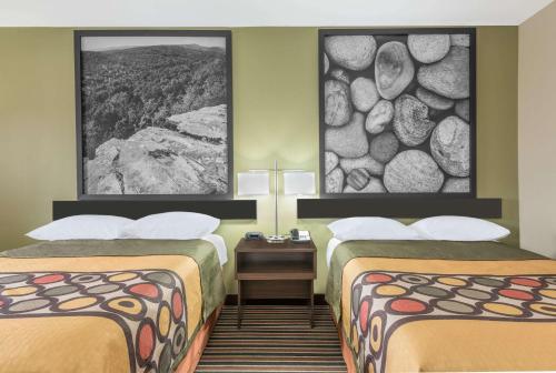 a hotel room with two beds and a stone wall at Super 8 by Wyndham Bryant Little Rock Area in Bryant