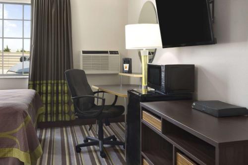a hotel room with a bed and a desk with a television at Super 8 by Wyndham Ardmore in Ardmore