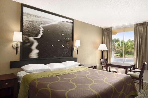 a hotel room with a bed with a large picture on the wall at Super 8 by Wyndham Ormond Beach in Ormond Beach