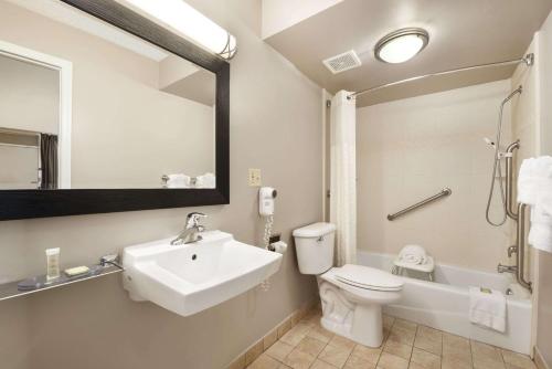 a bathroom with a sink and a toilet and a mirror at Super 8 by Wyndham Ormond Beach in Ormond Beach