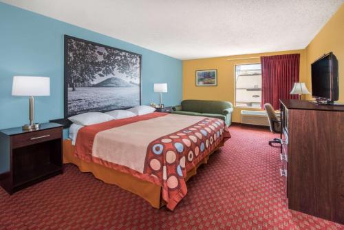 um quarto de hotel com uma cama grande e uma televisão em Super 8 by Wyndham Troy IL/St. Louis Area em Troy