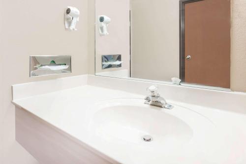 La salle de bains est pourvue d'un lavabo blanc et d'un miroir. dans l'établissement Super 8 by Wyndham Bolivar, à Bolivar