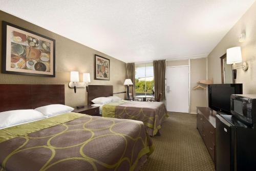 a hotel room with two beds and a flat screen tv at Super 8 by Wyndham Ormond Beach in Ormond Beach