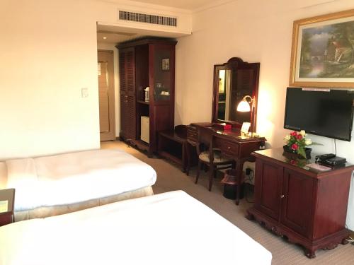 a hotel room with a bed and a desk and a television at Sunrise Hotel in Tainan