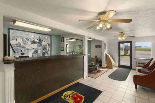 a living room with a bar with a ceiling fan at Super 8 by Wyndham Park City/North Wichita Area in Park City