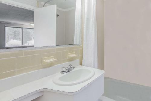 Super 8 by Wyndham W Yarmouth Hyannis/Cape Cod في يارموث الغربية: حمام أبيض مع حوض ومرآة