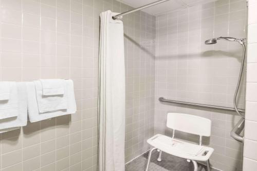 a bathroom with a shower with a white chair at Super 8 by Wyndham Luverne in Luverne