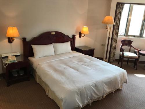 台南的住宿－日升大飯店，一间卧室配有一张带两盏灯的大型白色床。