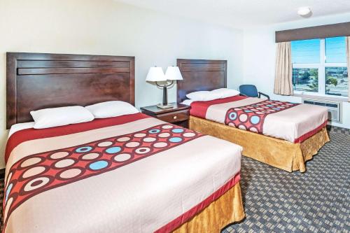 a hotel room with two beds and a window at Super 8 by Wyndham Calgary/Airport in Calgary