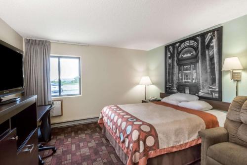 a hotel room with a bed and a flat screen tv at Super 8 by Wyndham Luverne in Luverne