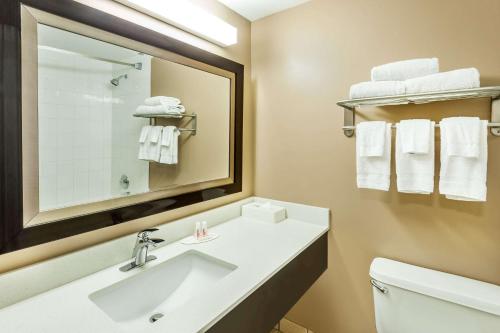 a bathroom with a sink and a mirror and towels at Super 8 by Wyndham Calgary/Airport in Calgary