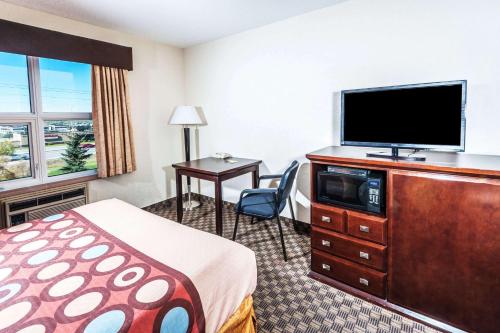 a hotel room with a bed and a flat screen tv at Super 8 by Wyndham Calgary/Airport in Calgary