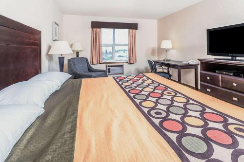 a hotel room with a large bed and a flat screen tv at Super 8 by Wyndham Calgary/Airport in Calgary