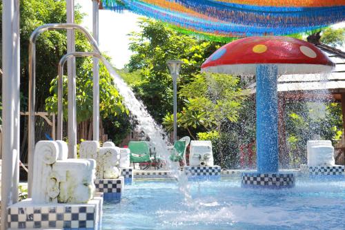 a pool with a water fountain with a red umbrella at The Mudan in Checheng
