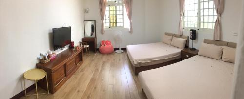 a living room with a bed and a tv at Dilly Dally B&B in Gukeng