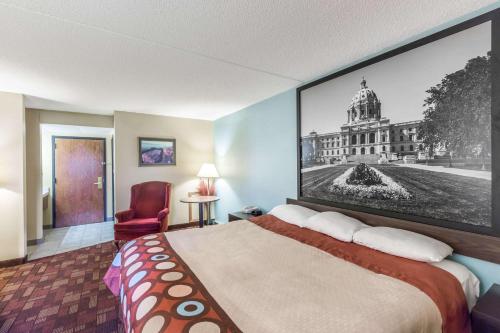 a hotel room with a bed with a picture on the wall at Super 8 by Wyndham Luverne in Luverne