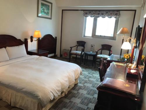 a hotel room with a bed and a table and chairs at Sunrise Hotel in Tainan