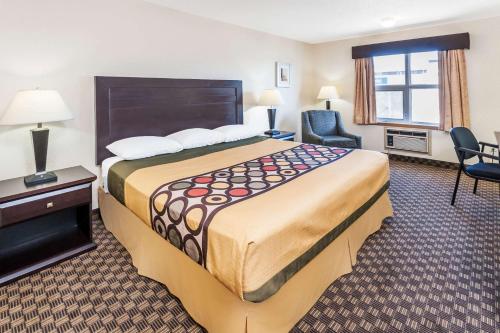a hotel room with a large bed and a chair at Super 8 by Wyndham Calgary/Airport in Calgary