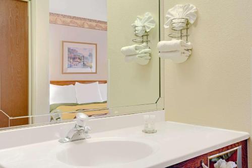 ein Bad mit einem Waschbecken und einem Spiegel in der Unterkunft Royal Inn Airport Salt Lake City in Salt Lake City