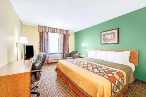 a hotel room with a large bed and a desk and a desk at Super 8 by Wyndham McKinney/Plano Area in McKinney