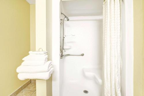 a bathroom with a shower and white towels at Super 8 by Wyndham McKinney/Plano Area in McKinney