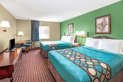 a hotel room with two beds and a flat screen tv at Super 8 by Wyndham McHenry Fox Lake Area in McHenry