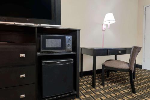 a hotel room with a desk with a microwave and a television at Super 8 by Wyndham Lithonia in Decatur