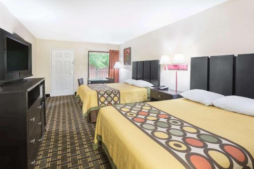 a hotel room with three beds and a flat screen tv at Super 8 by Wyndham Decatur/Lithonia/Atl Area in Decatur