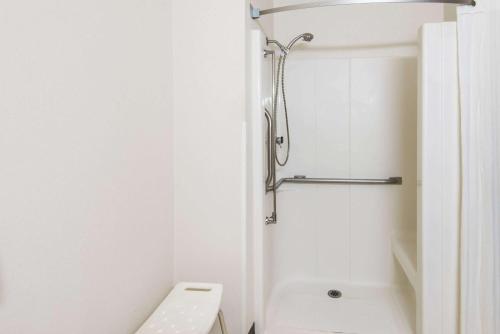 y baño blanco con aseo y ducha. en Super 8 by Wyndham Richfield Cleveland, en Richfield