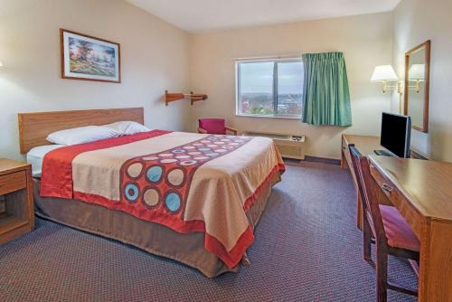 a hotel room with a bed and a desk and a computer at Super 8 by Wyndham Richfield Cleveland in Richfield