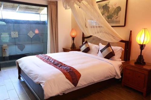 a bedroom with a bed and two lamps and a window at The Mudan in Checheng