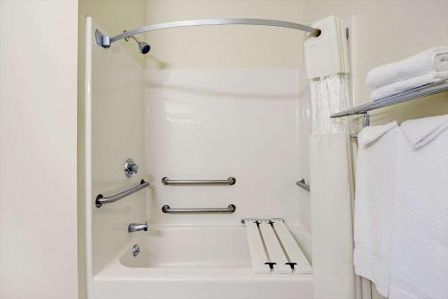 a white bathroom with a shower and a tub at Travelodge by Wyndham St. Louis in Berkeley
