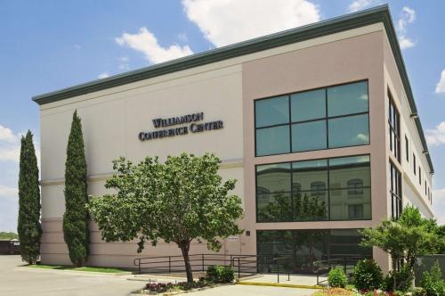 a building with a tree in front of it at Wingate by Wyndham and Williamson Conference Center in Round Rock