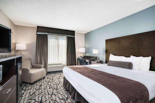 Cette chambre comprend un grand lit et une télévision à écran plat. dans l'établissement Days Inn & Suites by Wyndham Wausau, à Wausau