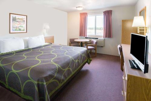 レドモンドにあるSuper 8 by Wyndham Redmondのベッド1台、薄型テレビが備わるホテルルームです。