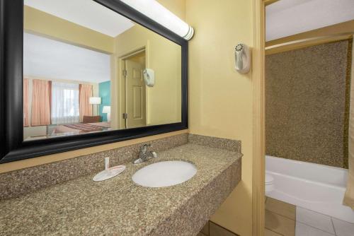 a bathroom with a sink and a mirror and a tub at Super 8 by Wyndham Tulsa in Tulsa