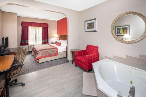 a hotel room with a tub and a bedroom at Ramada by Wyndham Alpharetta Atlanta North in Alpharetta