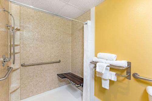 ein Bad mit einer Dusche, einem WC und Handtüchern in der Unterkunft Super 8 by Wyndham Clarinda in Clarinda