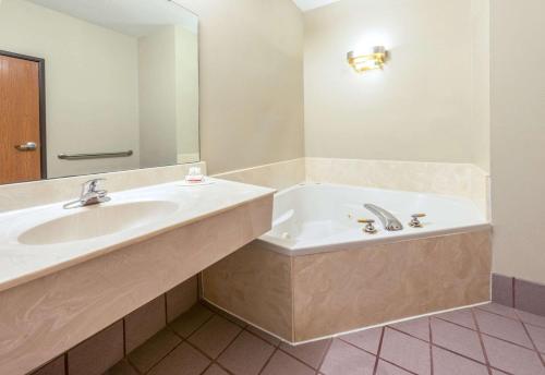 a bathroom with a tub and a sink and a mirror at Super 8 by Wyndham Pevely in Pevely