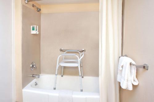 y baño con bañera y silla. en Super 8 by Wyndham Chicago/Rosemont/O'Hare/SE en River Grove