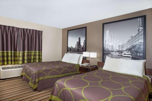 a hotel room with two beds and a window at Super 8 by Wyndham Chicago/Rosemont/O'Hare/SE in River Grove
